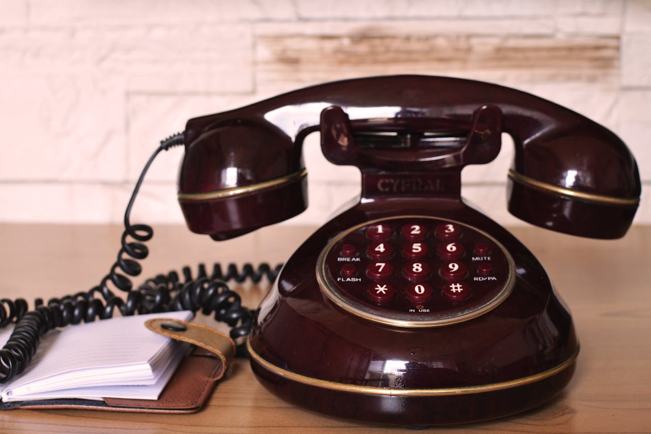Classic vintage rotary telephone with a coiled cord on a wooden desk, evoking nostalgia.